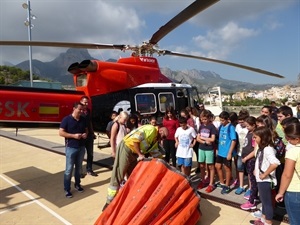El téncio de la brigada helitransportada de la Generalitat Valenciana explicando como coge agua el helicóptero a un grupo del C.P. Sant Rafel junto a Bernabé Cano, alcalde de La Nucía y Sergio Villalba, concejal de Educación